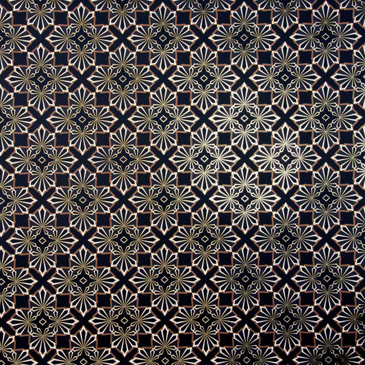 Blaze is a repeating shimmering geometric pattern featuring four black and white cannabis and marijuana leaves thinly framed in brown digitally printed on gold mylar shown illuminated in light bouncing off the gold trim outlining the pattern