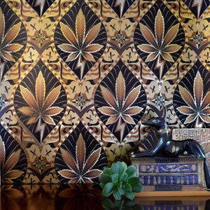 High Style High Baller is a gothic revival inspired cannabis marijuana grass weed themed repeat pattern wallpaper featuring joints, buds, cannabis leaves, smoke motif, in blacks, metallic browns, all outlined in gold and digitally printed on gold mylar - shown here in a vignette with a plant and ancient Egyptian sculptures