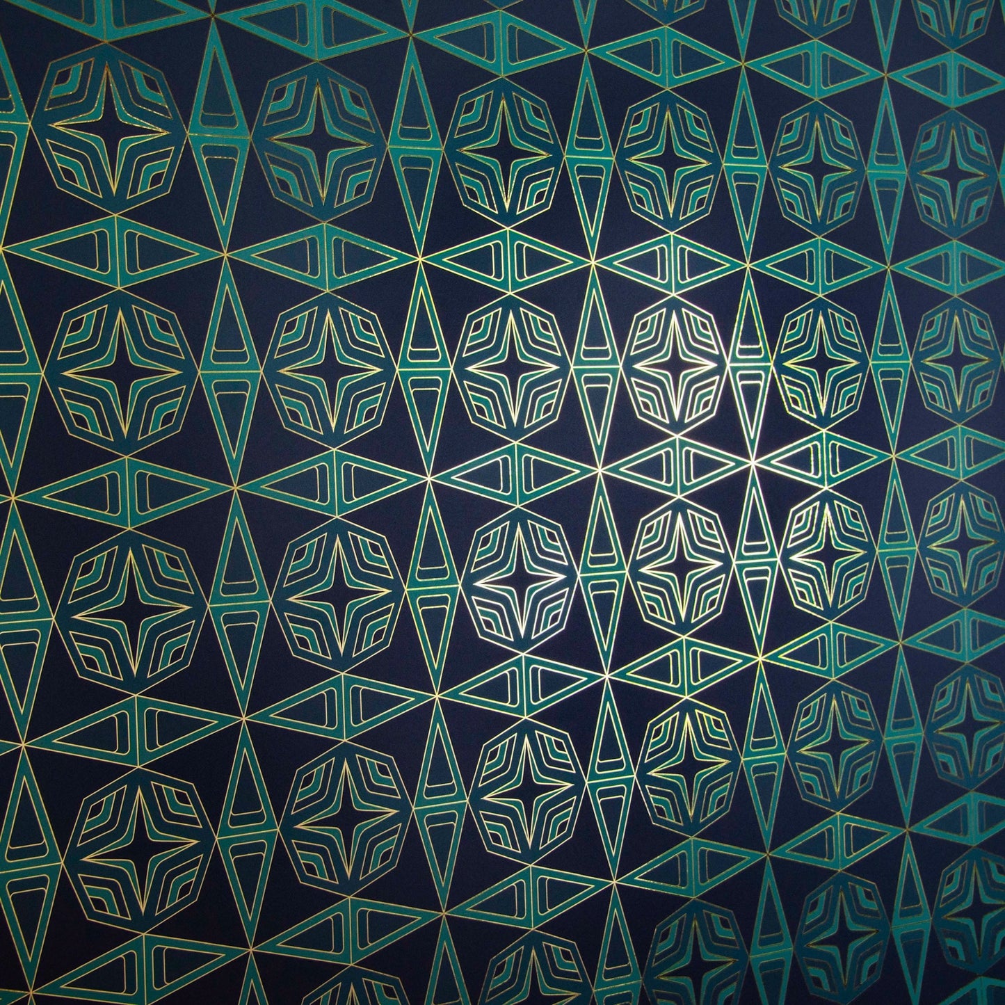 Integratronic Plush is a mid-century retro repeat geometric pattern featuring motifs in various greens on a darkest green background all outlined in gold and digitally printed on gold mylar - shown here at an angle with light illuminating the gold outlines