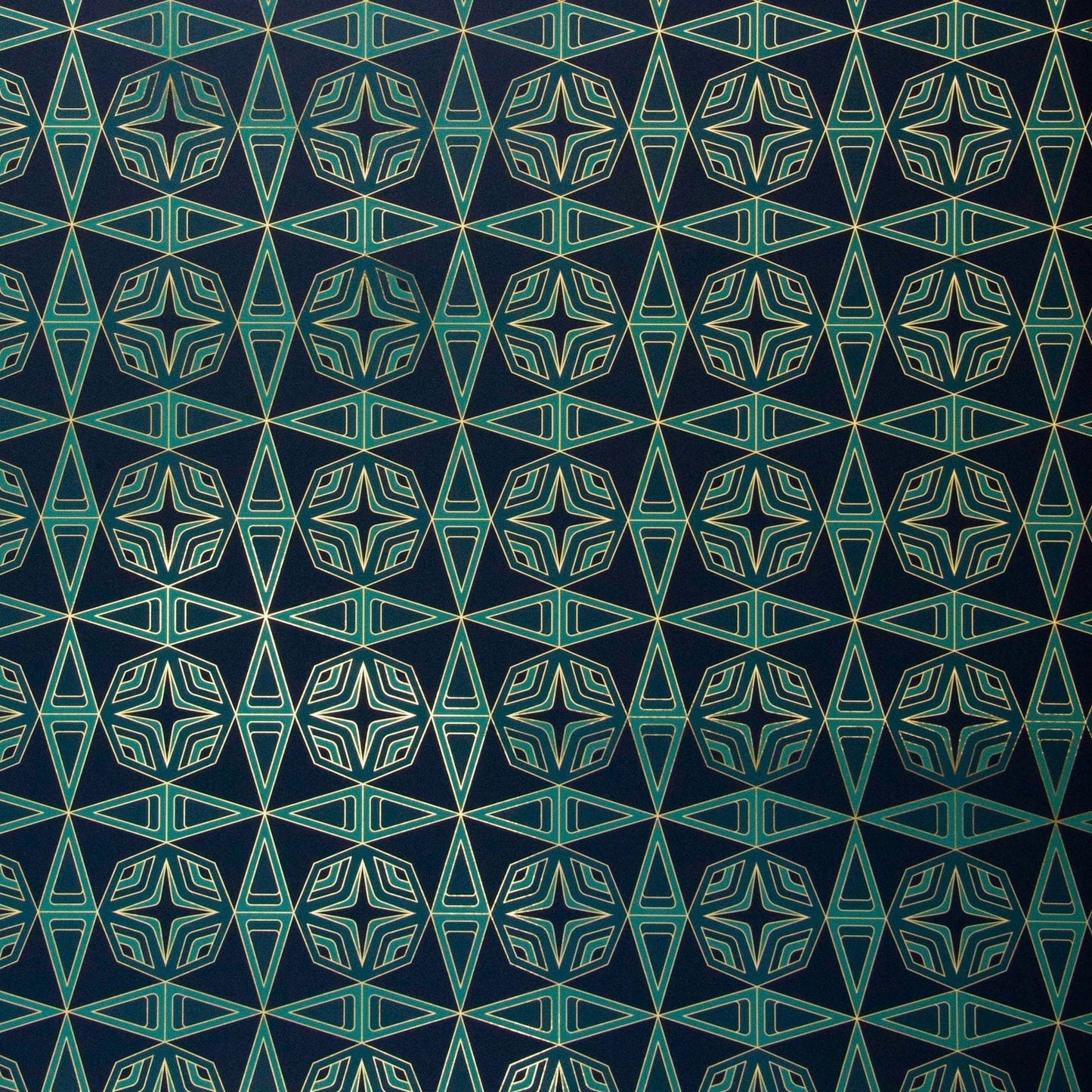 Integratronic Plush is a mid-century retro repeat geometric pattern featuring motifs in various greens on a darkest green background all outlined in gold and digitally printed on gold mylar - shown here at an angle with light illuminating the gold outlines