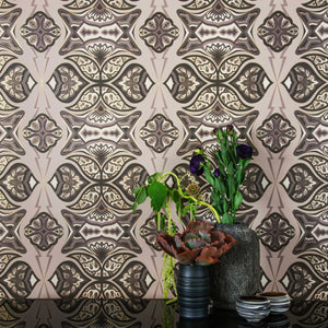 Ulu Dunes is a graphic repeat pattern featuring various gold outlined organic motifs geometrically woven together in various grays and warm whites outlined in gold, digitally printed on gold mylar  and shown in a vignette with flowers in pottery vases
