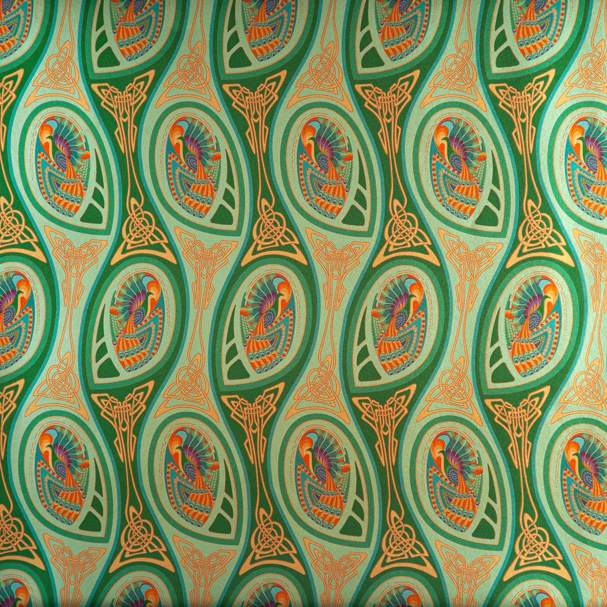 Peacock Nouveau Green Garden is a shimmering Celtic and Art Nouveau inspired maximalist repeat pattern wallpaper featuring peacocks and Celtic knot work in various greens, orange, blue, yellow, blues, purple, on a light green background, digitally printed on silver mylar