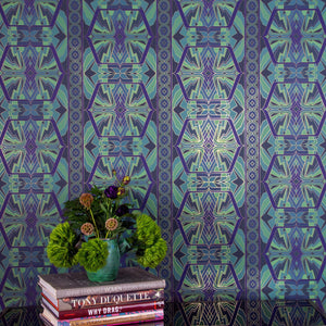 Sampa Undersea is a riff of a classical vintage repeat linear geometric pattern wallpaper in earth tones, blues and greens, with all shapes outlined in gold digitally printed on gold mylar - shown in a vignette with flowers and coffee table books.
