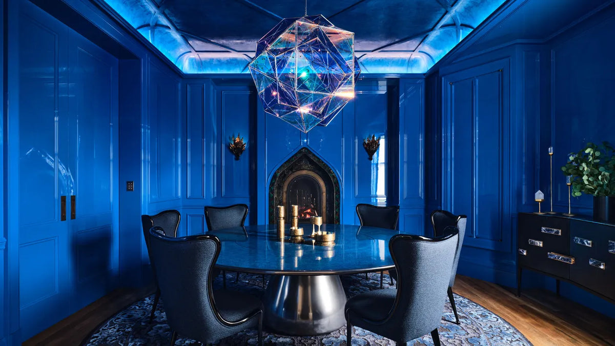 A modern dining room with high-gloss blue walls and a geometric chandelier.