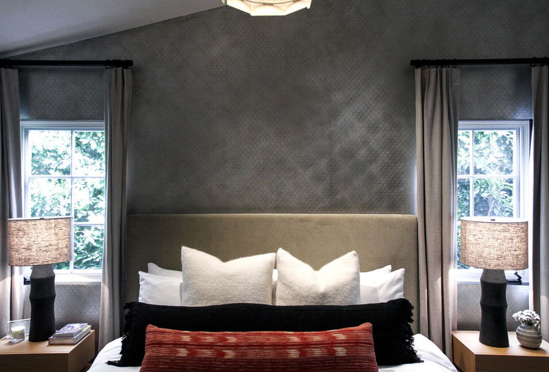 A bedroom featuring a metallic grey accent wall with a subtle textured pattern behind a bed.