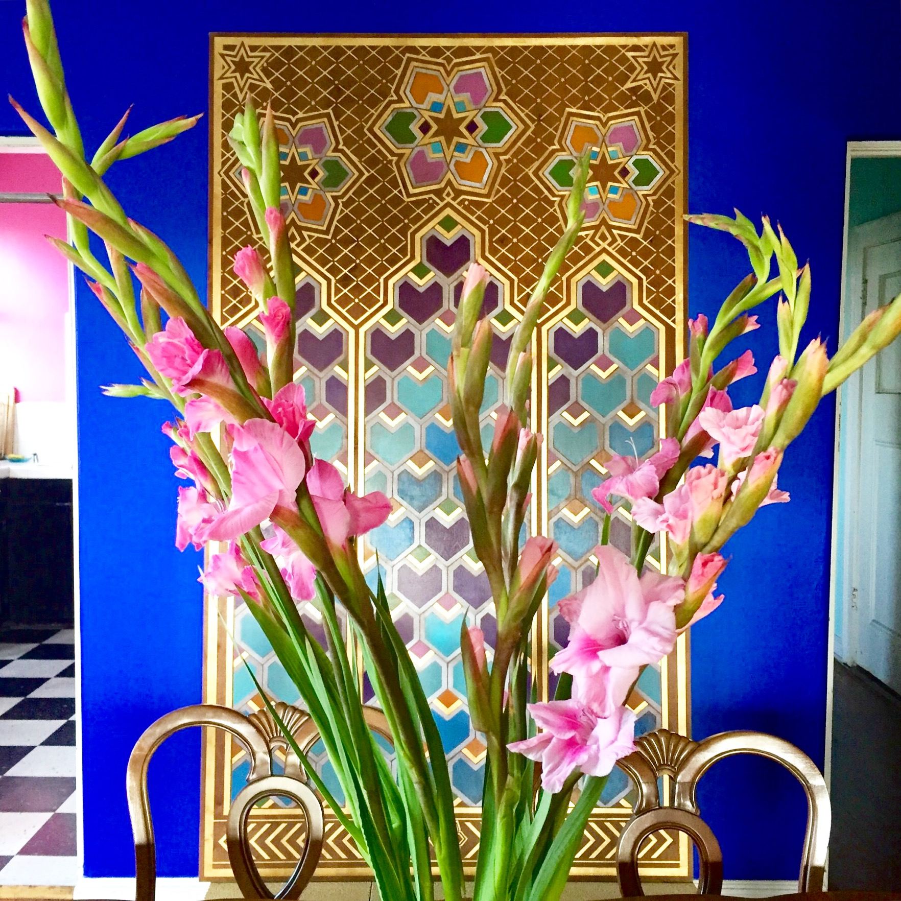 A custom Moroccan-inspired art panel with intricate gold and colorful geometric patterns on a blue wall.