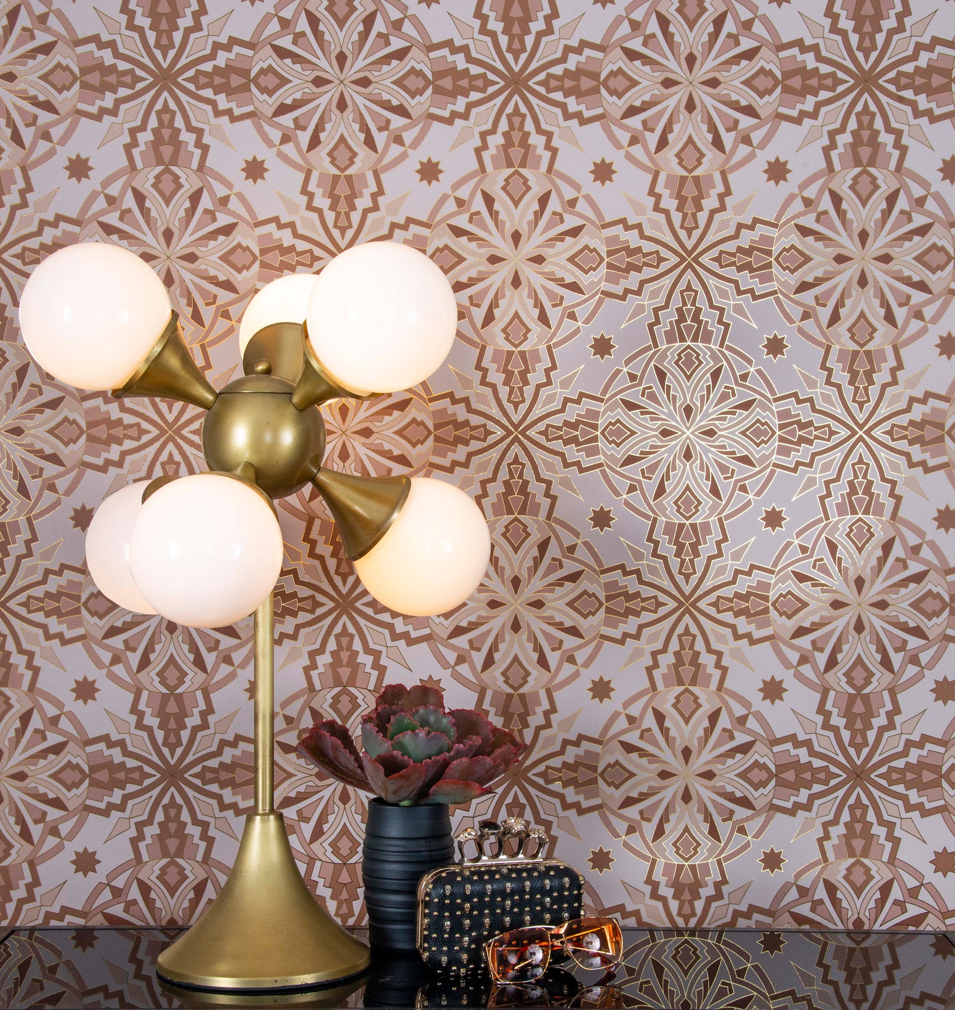 A modern brass lamp and accessories sit before a wall of geometric Star Guitar wallcovering.