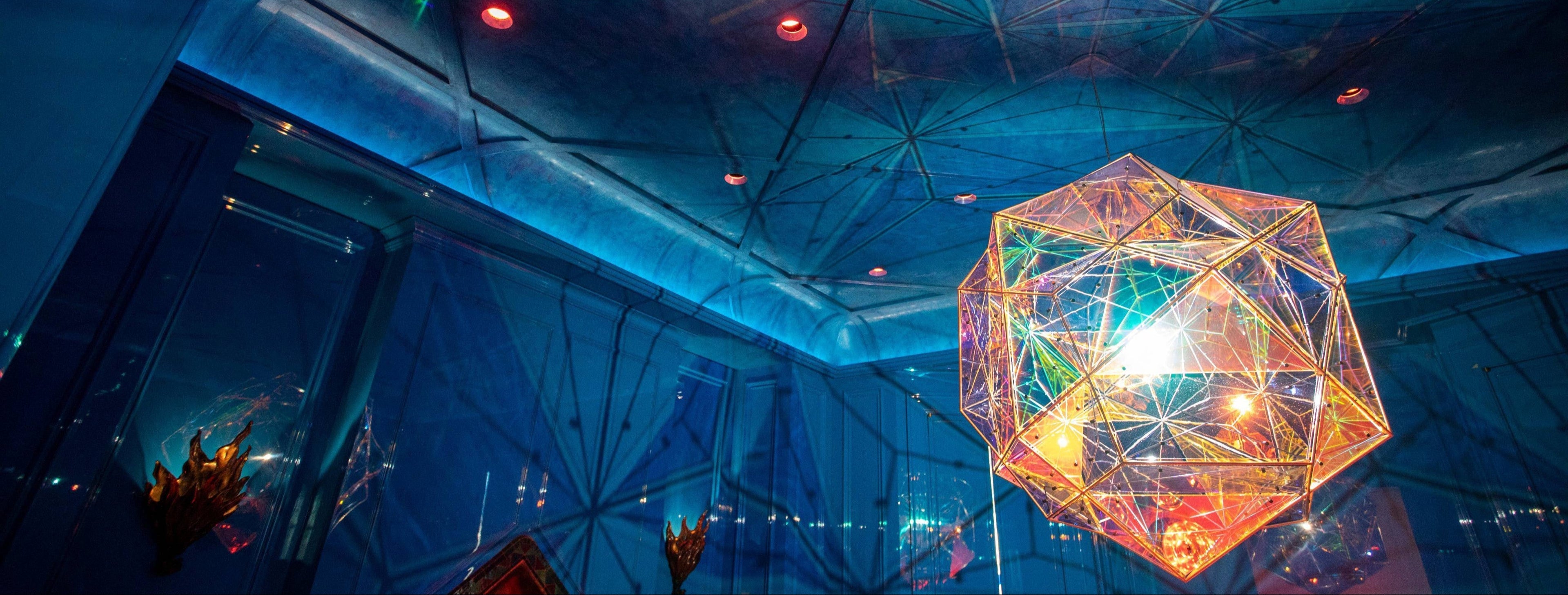 Colorful ceiling light by Olafur Eliasson suspended from a custom blue Venetian plaster ceiling by Londubh Studio in a high-gloss lacquered blue dining room designed by Nicole Hollis — a fusion of art, craftsmanship, and architectural elegance