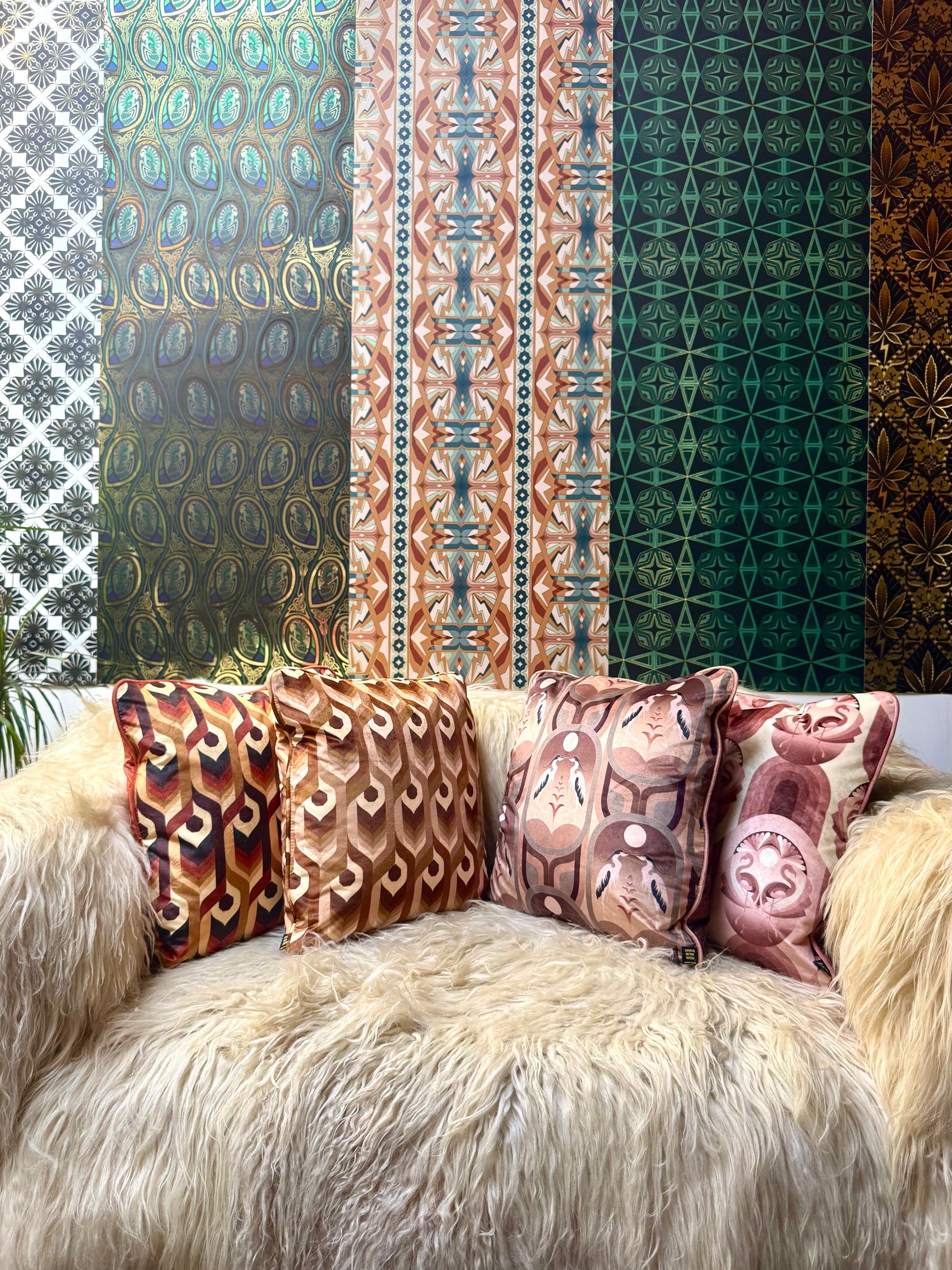 A sofa with Integratronic pillows in front of various Londubh Studio wallpaper samples.