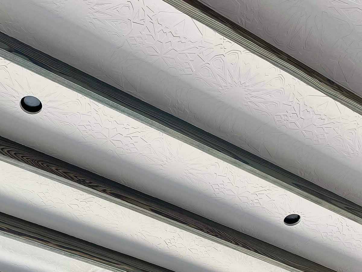 White ceiling panels with a textured Star Guitar pattern between dark wood beams.