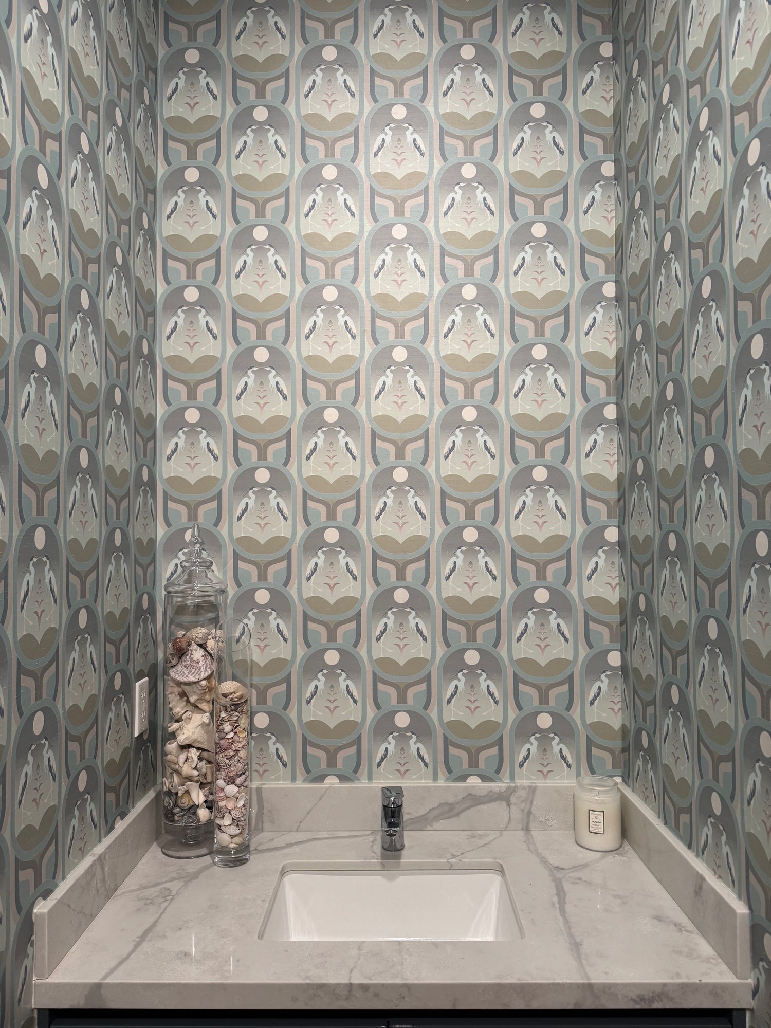 A bathroom featuring Cha Cha 'Chill' Wallcovering above a white sink and marble countertop.