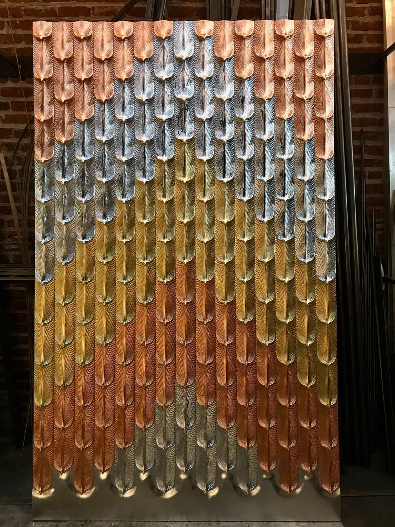 A large custom wall panel with a textured feather pattern in metallic silver, gold, and copper.