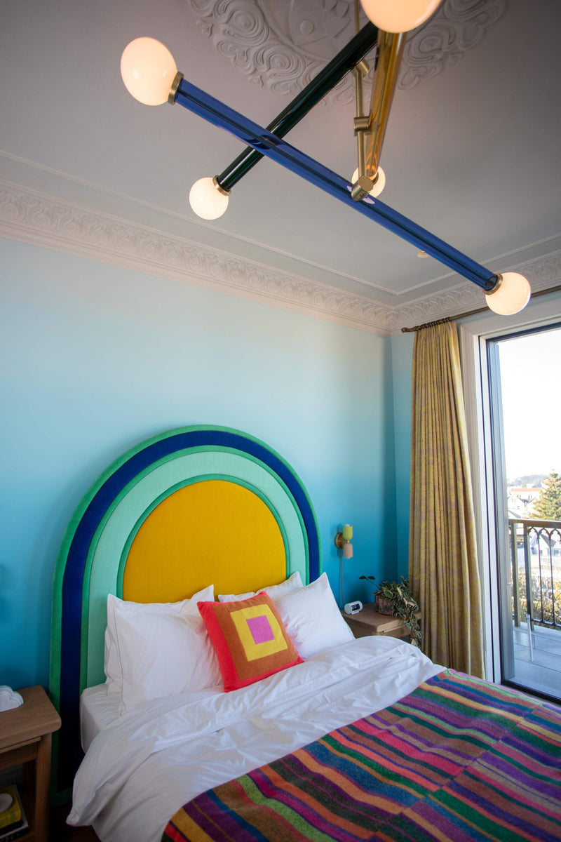 Bedroom with a colorful arched rainbow headboard and bright blue walls.