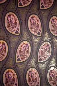 Peacock Nouveau Aubergine is a Celtic and Art Nouveau inspired maximalist repeat pattern wallpaper featuring peacocks and Celtic knot work in pinks, purples, all outlined in gold and digitally printed on gold mylar.