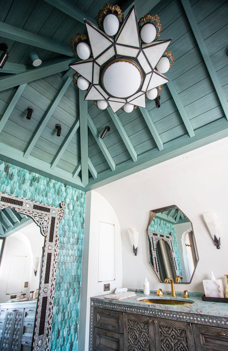 A Moroccan-style bathroom with a teal vaulted ceiling and iridescent scale-like tiles.