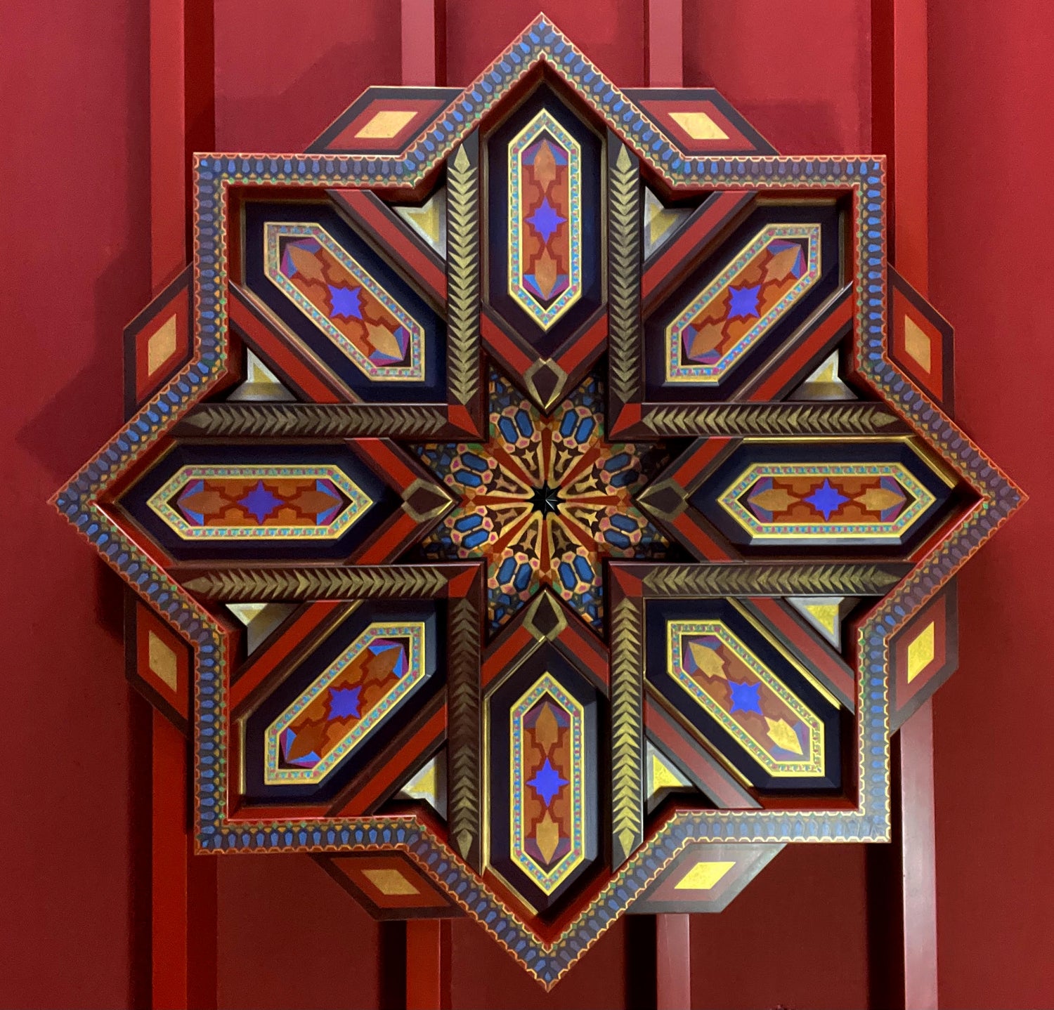 A detailed, hand-painted three-dimensional geometric star in red, blue, and gold.