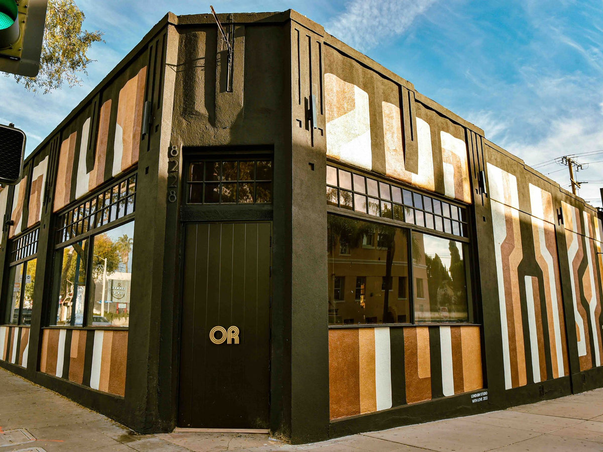 Angled corner view of the Open-Minded dispensary with a custom geometric mural by Londubh Studio.