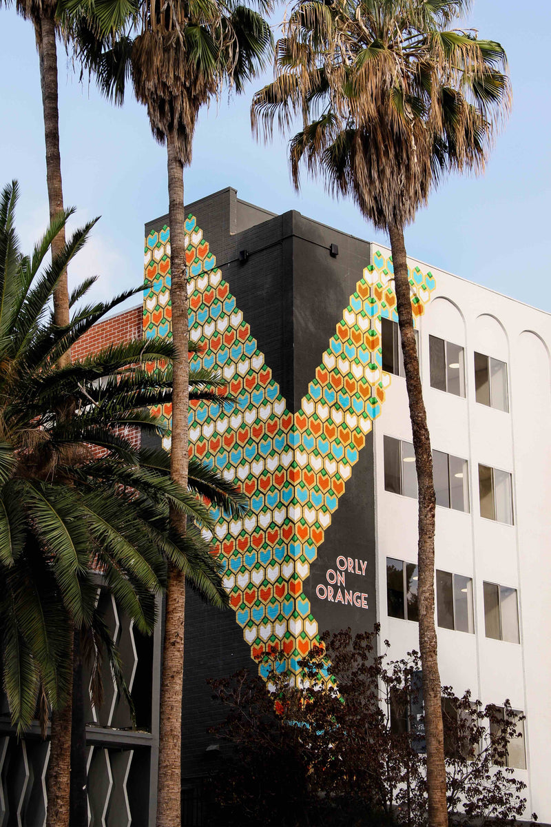 A vibrant custom mural with geometric shapes wraps around the corner of a modern building.