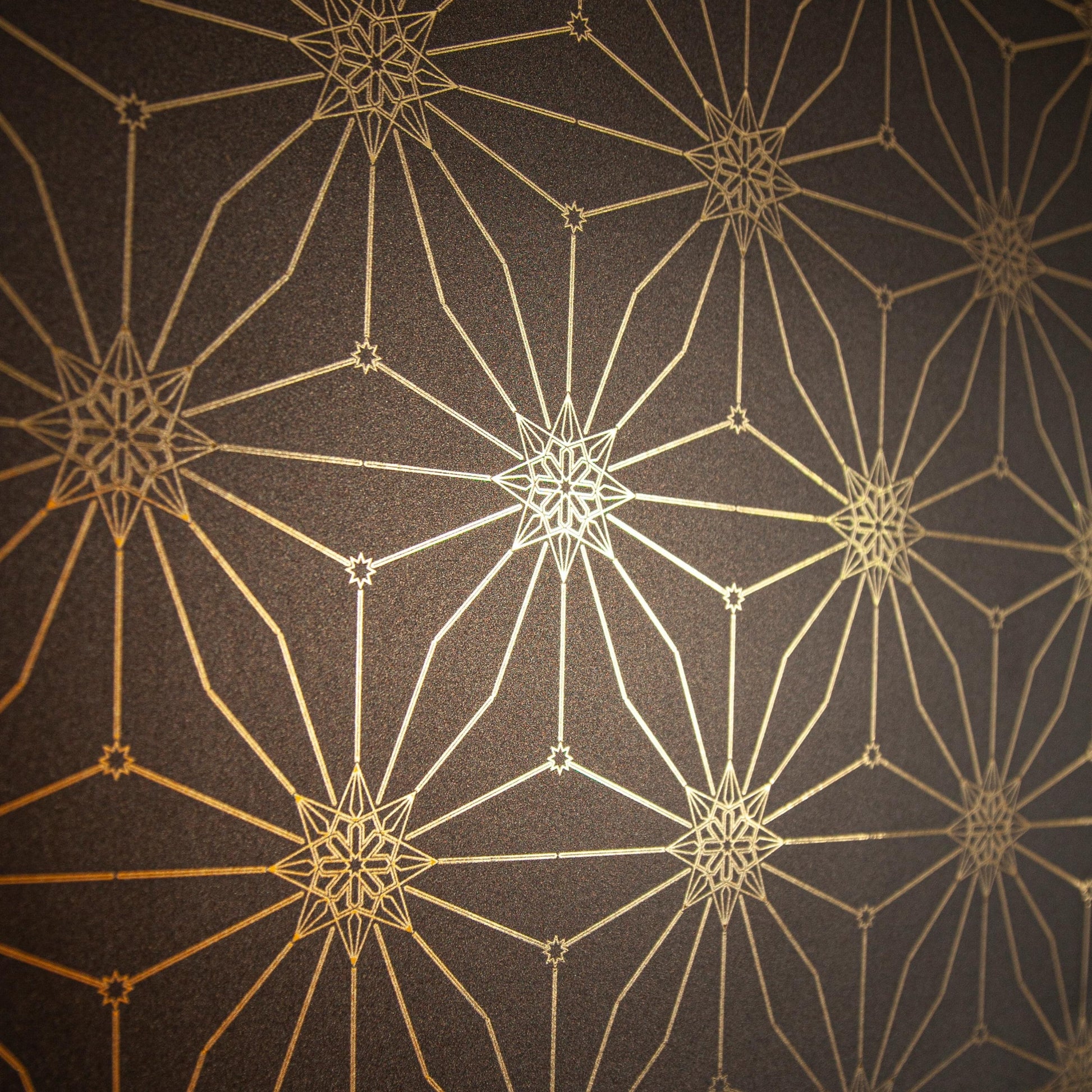 A detailed shot of Star Guitar 'Midnight' wallcovering with gold stars on a deep brown background.