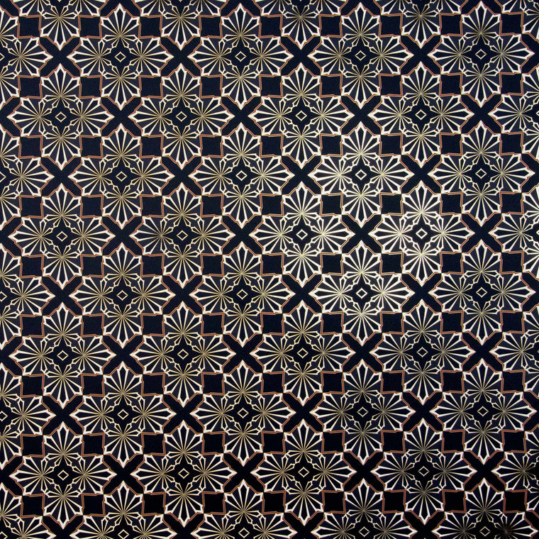 Blaze is a repeating shimmering geometric pattern featuring four black and white cannabis and marijuana leaves thinly framed in brown digitally printed on gold mylar shown illuminated in light bouncing off the gold trim outlining the pattern