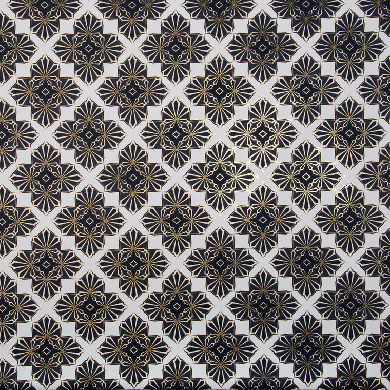 Blaze is a repeating shimmering geometric pattern featuring four black and white cannabis and marijuana leaves thinly framed in brown on a white background digitally printed on gold mylar shown illuminated in light bouncing off the gold trim outlining the pattern