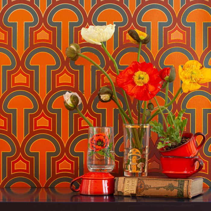 Poppies in vases against Enlightenment 'Panaeolus' wallcovering in orange and charcoal.