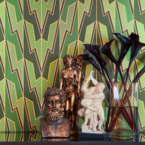 Greased Lightening Summer Storm is an art deco inspired gothamesque geometric repeat pattern showcasing the lightning bolt, in various greens, outlined in gold and printed on gold mylar - shown here in a vignette with miniature classical statue and flowers in a jar 