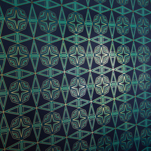 Integratronic Plush is a mid-century retro repeat geometric pattern featuring motifs in various greens on a darkest green background all outlined in gold and digitally printed on gold mylar  - shown here at an angle with light illuminating the gold outlines