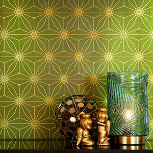 Star Guitar Magic Hour is a shimmering repeat moroccan inspired pattern and star motif linked together with a graphic thread in metallic green digitally printed on gold mylar shown in a vignette with a little sculpture and a light